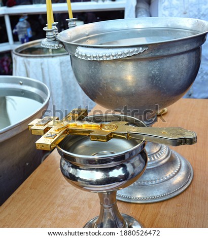 Orthodox gilded metal cross, prepared for the consecration of water, lies on a bowl. Holy Epiphany, Jordan. Consecration of water. The concept of Orthodoxy. Royalty-Free Stock Photo #1880526472