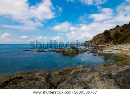 A beautiful coast view of clear blue sea, rocks, cliff and cloudy sky. Seascape of a bay.