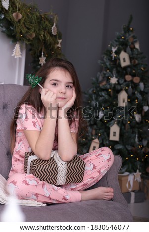 Portrait of a girl with long blond hair near the New Year tree, elegant festive Christmas card