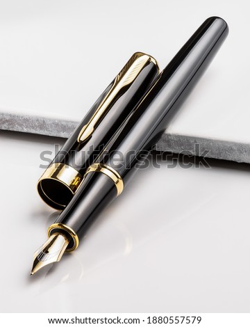 Fountain pen, black and gold color, on top of a beautiful white granite background closeup macro
