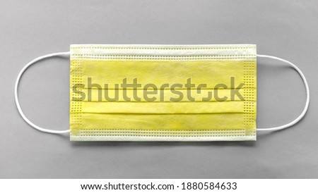Top view of medical protective yellow mask on gray background