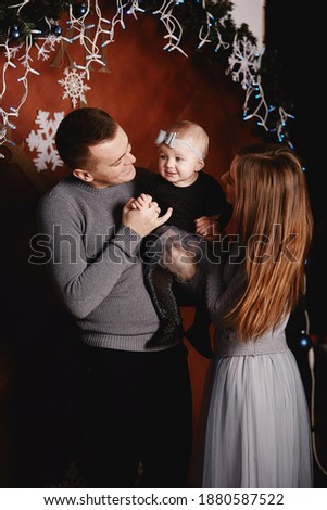 cute young family dad, mom and baby daughter are hugging and kissing on Christmas background. Merry Christmas and Happy New Year holidays
