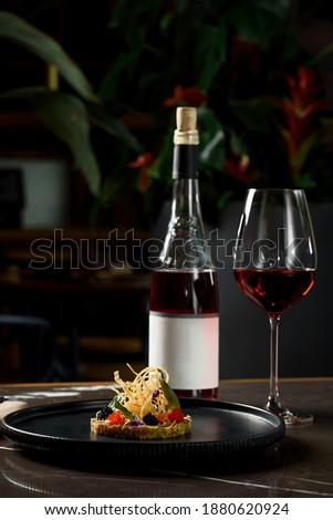 Concept of a food photography. One of the popular Vietnamese dish and wine glass of rose wine at the restaurant's table. Food photo with green plants background. Part of vietnamese cuisine