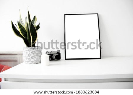 blank vertical frame mockup with flower pot, vintage camera and candle on the table