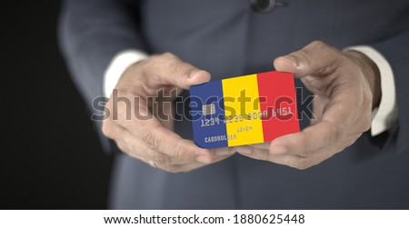 Businessman takes plastic bank card with printed flag of Romania, fictional numbers