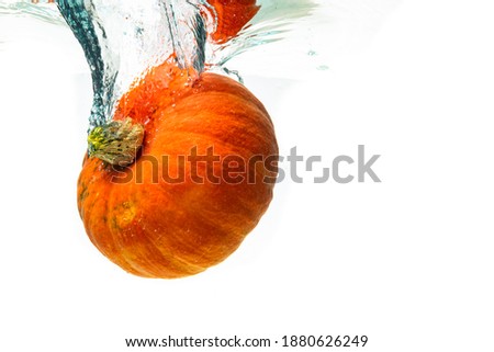 Orange pumpkin splashing into water isolated against white background. Healthy vegetables concept.