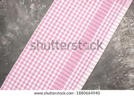 Overhead view of half-folded pink stripped towel lying on dark background