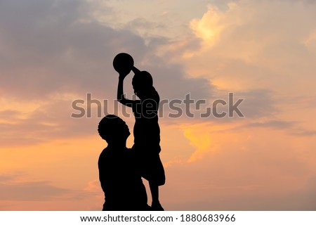 Silhouette of father and son with ball evening sky sunset background, Sport and enjoying life concepts.