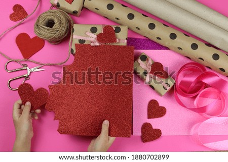 Children's hands packing gifts for the Valentine's Day holiday, a symbol of love. flat lay