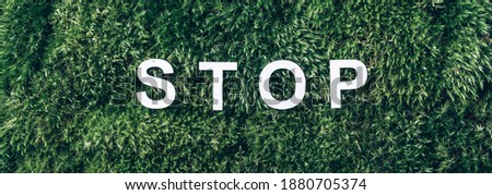 Word Stop on moss, green grass background. Top view. Copy space. Banner. Biophilia concept. Nature backdrop. stop environmental pollution.