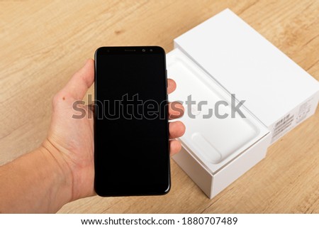 Picture of new smartphone unboxing in front of wooden background