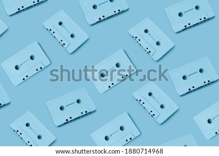 Pattern made with retro audio cassettes on pastel blue background. Creative concept of retro technology. 70's or 80's aesthetic. Flat lay, top view.