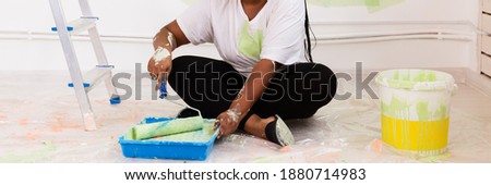 Smiling african american woman painting interior wall of home, close-up. Renovation, repair and redecoration concept.
