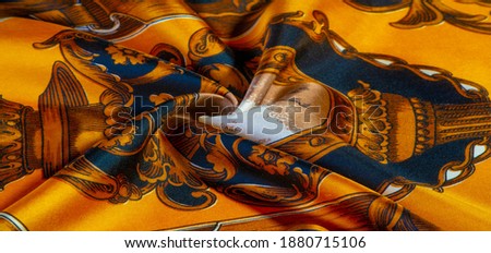 Yellow silk fabric with a gothic pattern. rich silk gothic prints in rich black and gold hues. Texture, background, pattern Royalty-Free Stock Photo #1880715106