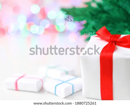 Gift with red ribbon, defocus light at the back. Several gifts on a festive background.