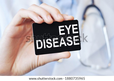 Doctor holding a black paper card with text EYE DISEASE, medical concept. EYE DISEASE card in hands of medical doctor