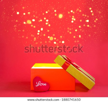 Open red gift box with a bow and a soft heart with the inscription Love in golden glow and glitter inside on a red background, banner, copyspace. universal holiday, valentine's day, new year, birthday