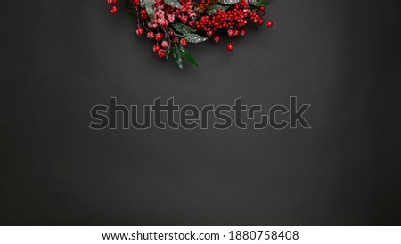 Part of a Christmas wreath from above (red berries with cones) on a black background. New Year's composition. template for text.