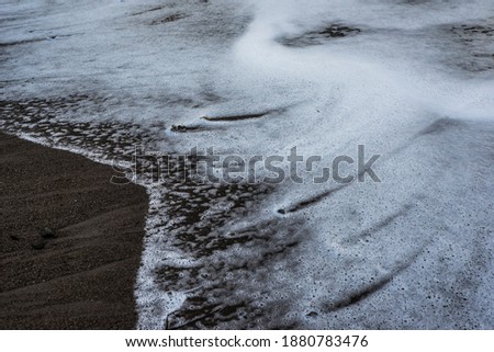 View of storm seascape, beach, waves. 
The waves breaking on beach, forming a spray.
