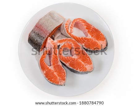 Fresh uncooked steaks of a rainbow trout on white dish on a white background, top view
