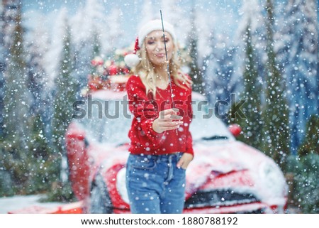 Outdoor portrait of a young beautiful happy smiling girl posing on the street next to a car. Winter fashion, Christmas holidays concept, out of focus shot for photo background. High quality photo.