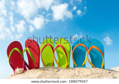 Row of colorful flip flops on beach against sunny sky