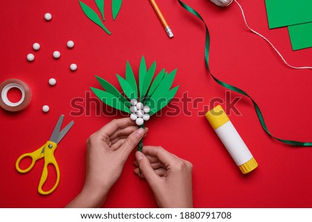 Woman making mistletoe branch on red background, top view