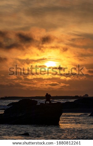 Silhouette of photographer taking pictures of sunrise at the seaside
