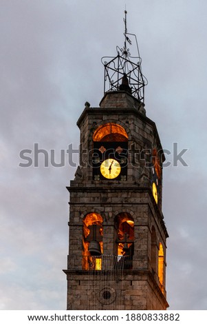 Vertical view of the bell tower Of the Church of Puebla de Sanabria with a sunset decorated with the Christmas lights of 2020