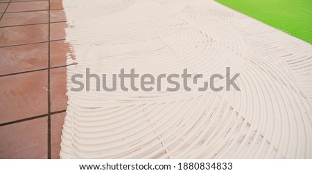 worker applying tile adhesive glue on the floor	 Royalty-Free Stock Photo #1880834833