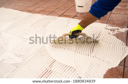 worker applying tile adhesive glue on the floor	 Royalty-Free Stock Photo #1880834839