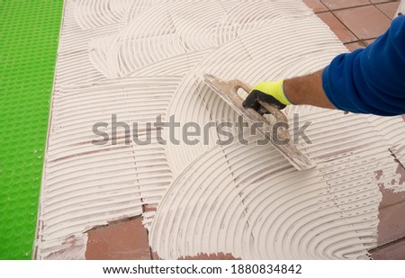 worker applying tile adhesive glue on the floor	 Royalty-Free Stock Photo #1880834842