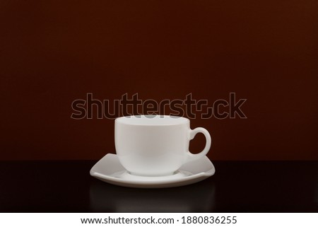 White coffee cup on black table against brown background with space for text