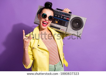 Photo of excited youth girl hold boom box show horned symbol wear yellow leather jacket isolated violet color background