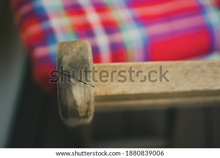 A top view closeup of an old wooden chair with a colorful checkered pillow on it