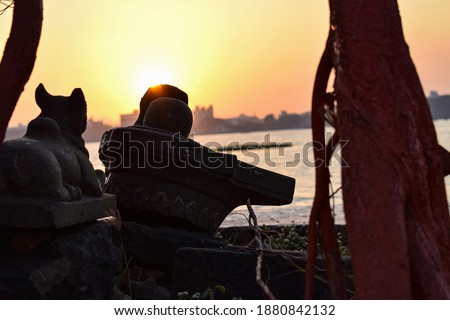 Picture of ancient shivling with statue of bull in the old city of India, there is beautiful sunset in the background