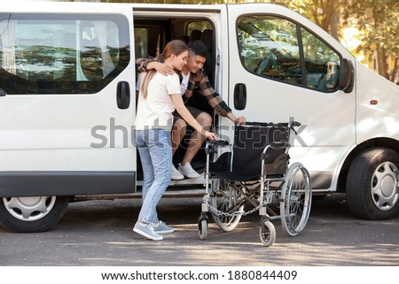 Woman helping her handicapped husband to get out of van Royalty-Free Stock Photo #1880844409