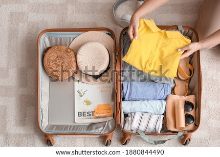 Woman packing suitcase at home. Travel concept Royalty-Free Stock Photo #1880844490