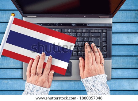 woman hands and flag of Thailand on computer, laptop keyboard 