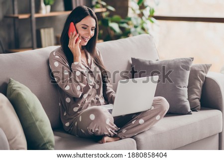 Photo of nice optimistic girl sit write laptop talk telephone wear pijama at home