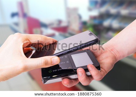 Pos terminals and smartphone. In the background is a supermarket checkout. Banking equipment. Acquiring. Acceptance of bank credit cards. Contactless payment.	
