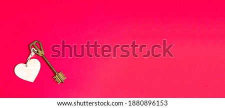 Golden key with wooden tag in the shape of a heart on a red background. Valentine's day, Declaration of love, copy space. Open, closed feelings. Sweet home, real estate