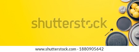 Different gray empty ceramic plates on yellow background, trendy colors 2021, banner size, Top View, Copy Space