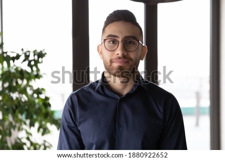 Headshot portrait of young Arabic male employee in glasses pose in office workplace. Profile picture of successful confident millennial arab businessman in spectacles show leadership and motivation.