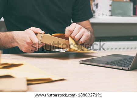 The man is packing the product into the yellow envelope