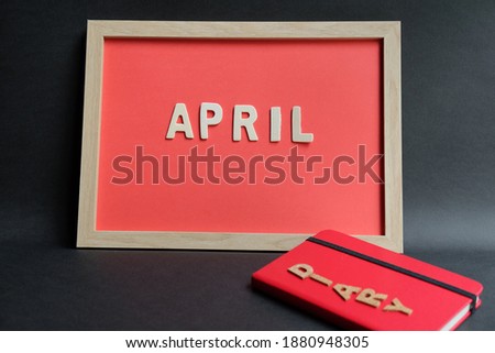 Diary book, black pen and April
 word wooden in frame on black background. Business, weekend, holiday or new year planning concept.