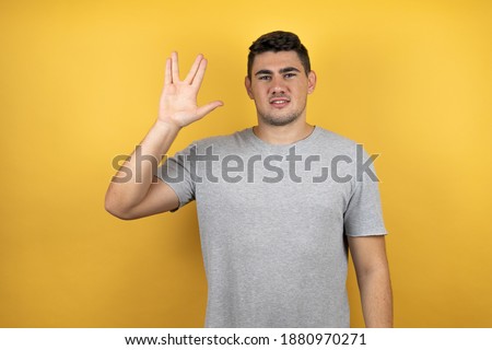 Young handsome man wearing a casual t-shirt over isolated yellow background doing hand symbol