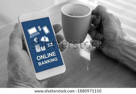 Male hands holding a smartphone with online banking concept and a cup of coffee