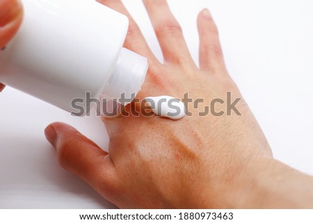 Applying moisturizing cream to Asian man's dry hands. Royalty-Free Stock Photo #1880973463