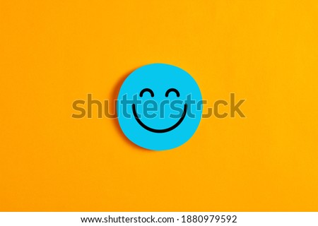 Blue round circle with a happy face icon against yellow background. Positive expression or customer satisfaction in business concept.  Royalty-Free Stock Photo #1880979592